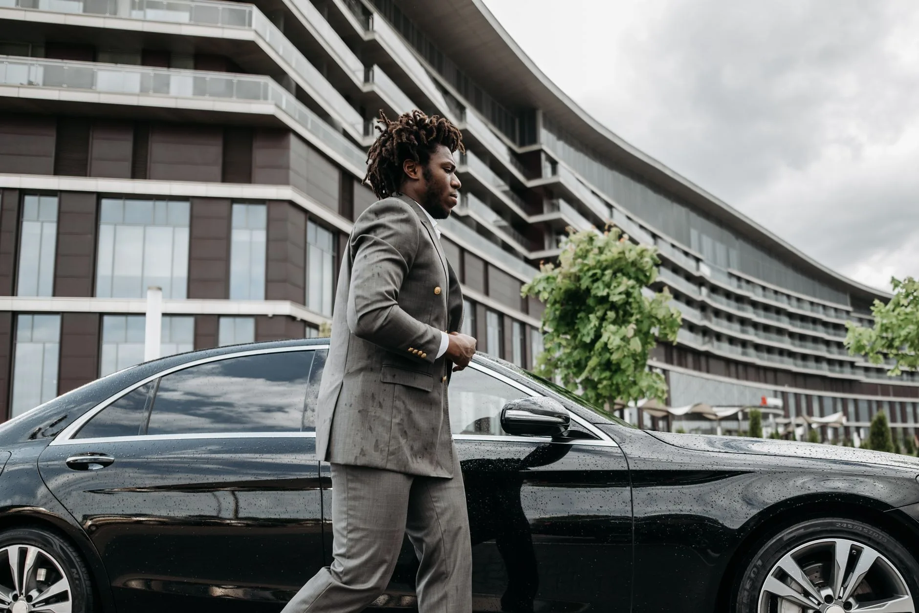 An executive stepping out of a luxury car outside a business conference center.