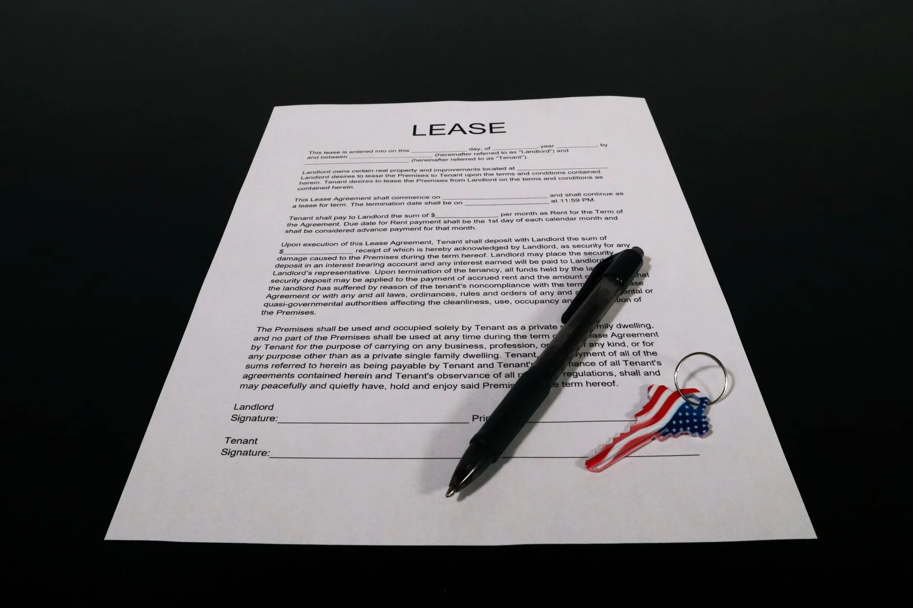 Hands signing a car rental agreement on a desk with a set of keys nearby.